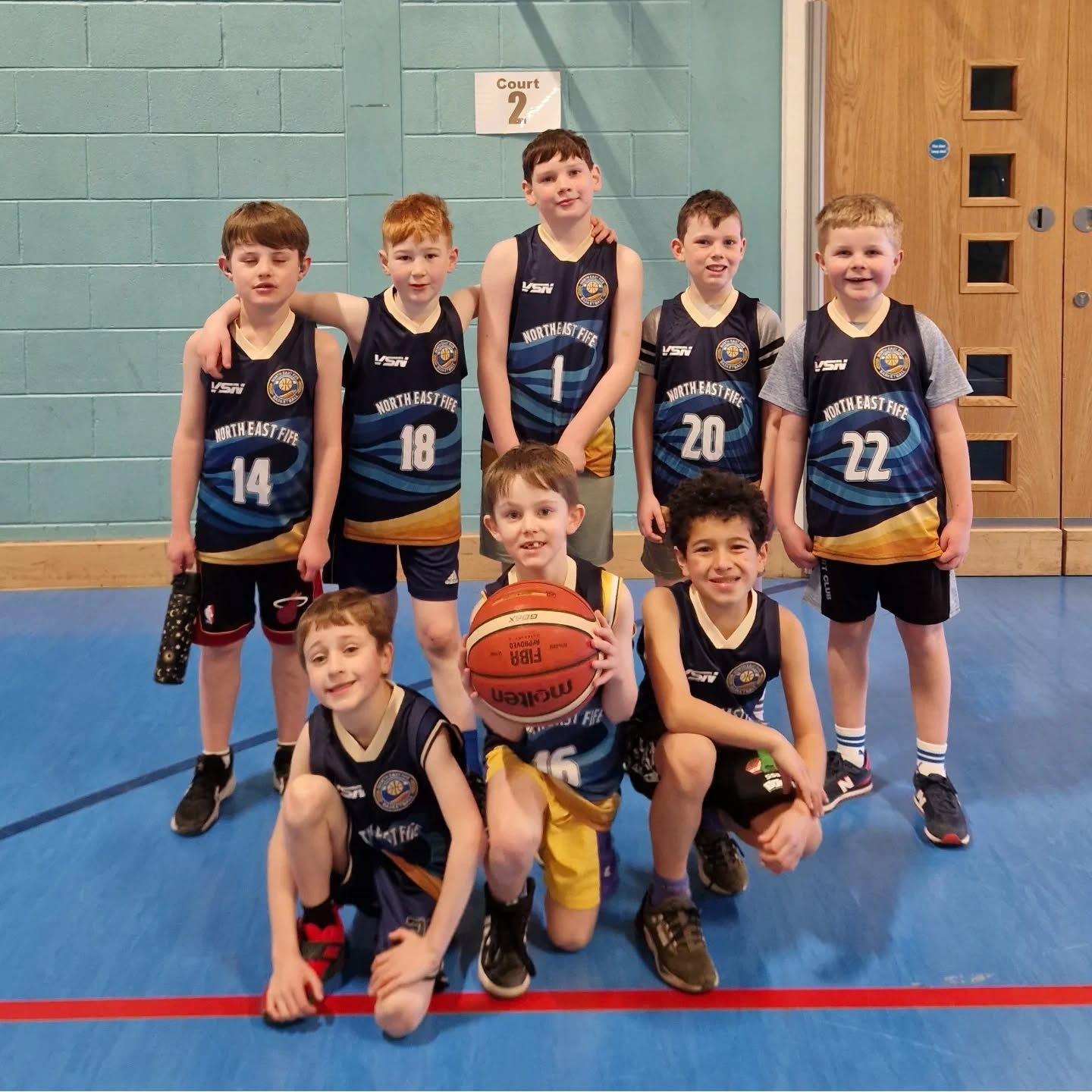 Young North East Fife Basketball players smiling together in club kit