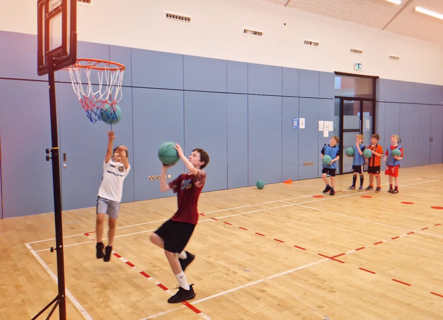 Young basketball players taking turns during a finishing challenge