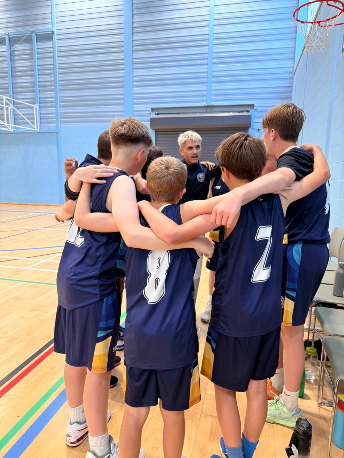 North East Fife Basketball players and their coach gathered in a team huddle